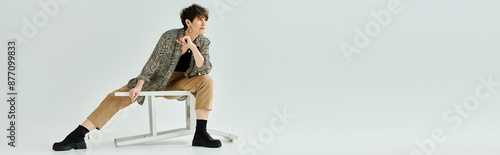 Obraz na plátně A middle-aged woman with short hair sitting on a chair, crossing her legs in a stylish and elegant manner in a studio setting