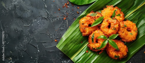 Kerala's Parippu Vada, a traditional South Indian snack, is displayed on a dark background. The savory fried treats are arranged atop a banana leaf with copy space image. photo