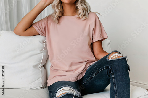 Blank pink oversize t-shirt on a woman model sitting on the sofa. Minimalist Trendy t-shirt mockup.