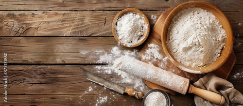 Top view of a pastry board with a knife, rolling pin, and flour, perfect for adding text, against a wooden backdrop with a bowl of flour. Ideal for a copy space image. photo