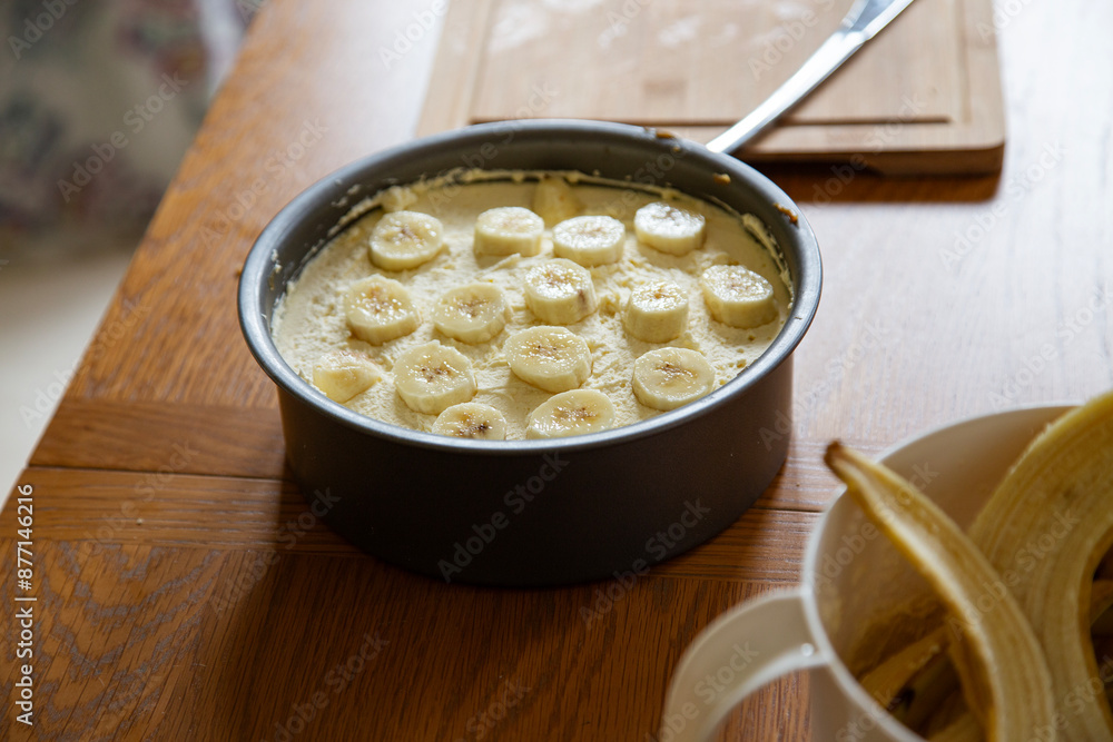 A banoffee pie in the making, resting on a naturally lit wooden table with banana skins in a bowl A banoffee pie in the making, resting on a naturally lit wooden table with banana skins in a bowl