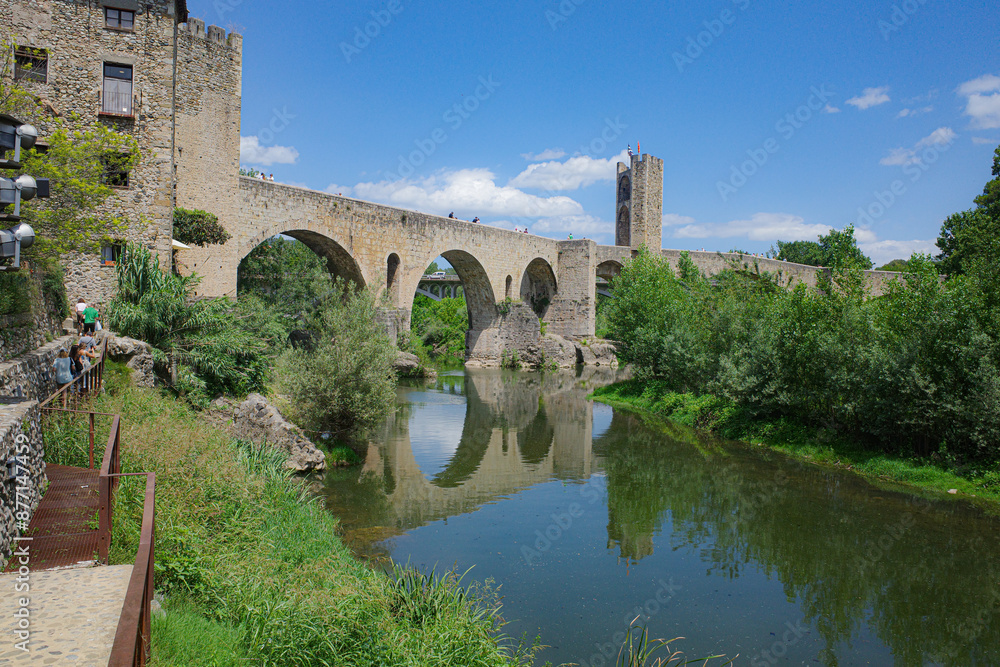 Girona, Spain - 7 July, 2024: Reflections of the medieval Pont Vell bridge on the River Fluvia at Besalu, Catalonia Girona, Spain - 7 July, 2024: Reflections of the medieval Pont Vell bridge on the River Fluvia at Besalu, Catalonia