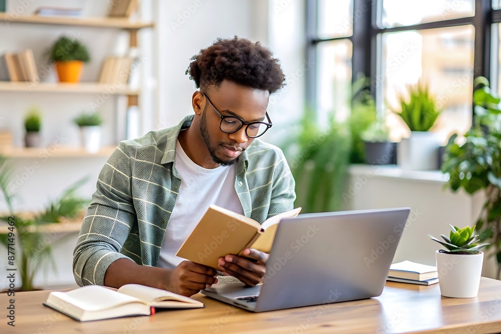 Man reading a book at his desk with a laptop. Man reading a book at his desk with a laptop.
