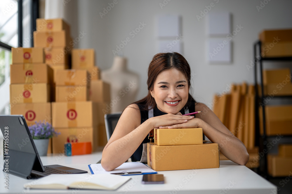 A woman is sitting at a desk with a laptop and a stack of boxes in front of her A woman is sitting at a desk with a laptop and a stack of boxes in front of her