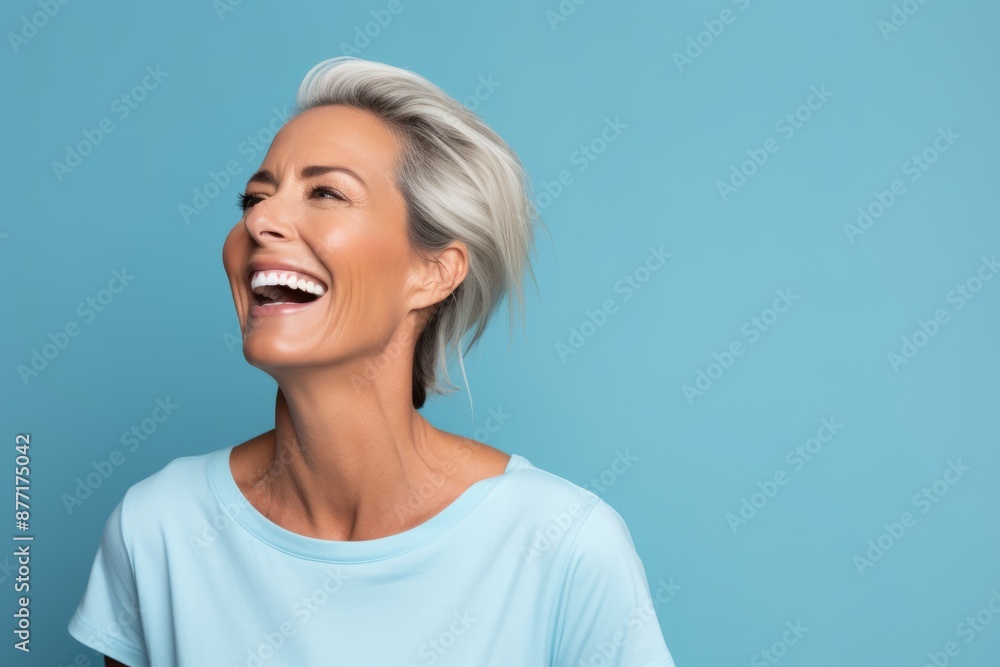 Beauty portrait of happy mature woman laughing and looking away against blue background