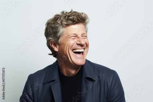 Portrait of a senior man laughing against a grey background with copy space