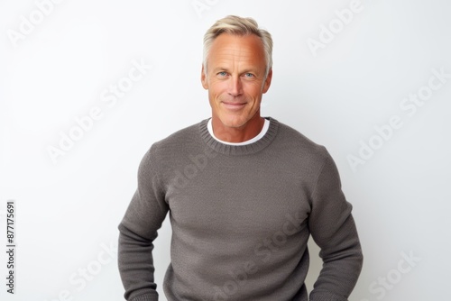 Portrait of handsome mature man looking at camera and smiling while standing against white background