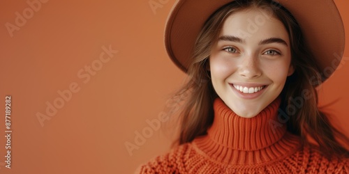 Portrait of a smiling young woman wearing an orange sweater and hat against an orange background. Generated AI