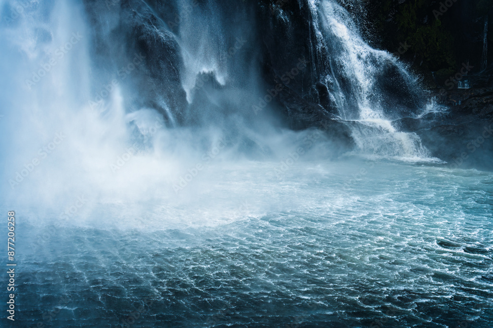 Naklejka premium Moody waterfall flowing in tropical rainforest at Milford Sound
