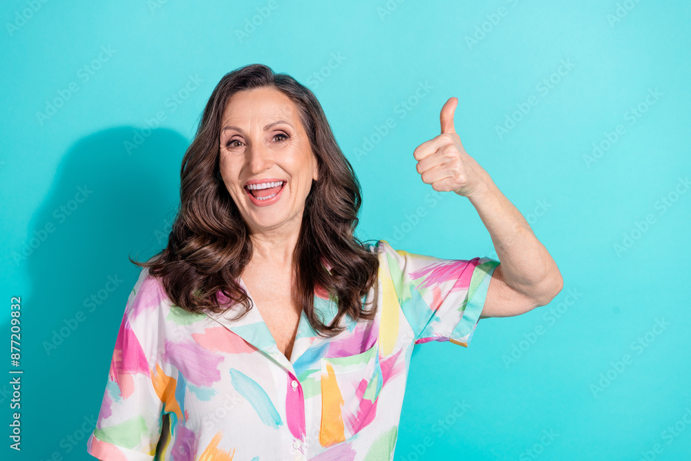 Photo portrait of lovely pensioner lady thumb up approve dressed stylish colorful garment isolated on cyan color background Photo portrait of lovely pensioner lady thumb up approve dressed stylish colorful garment isolated on cyan color background