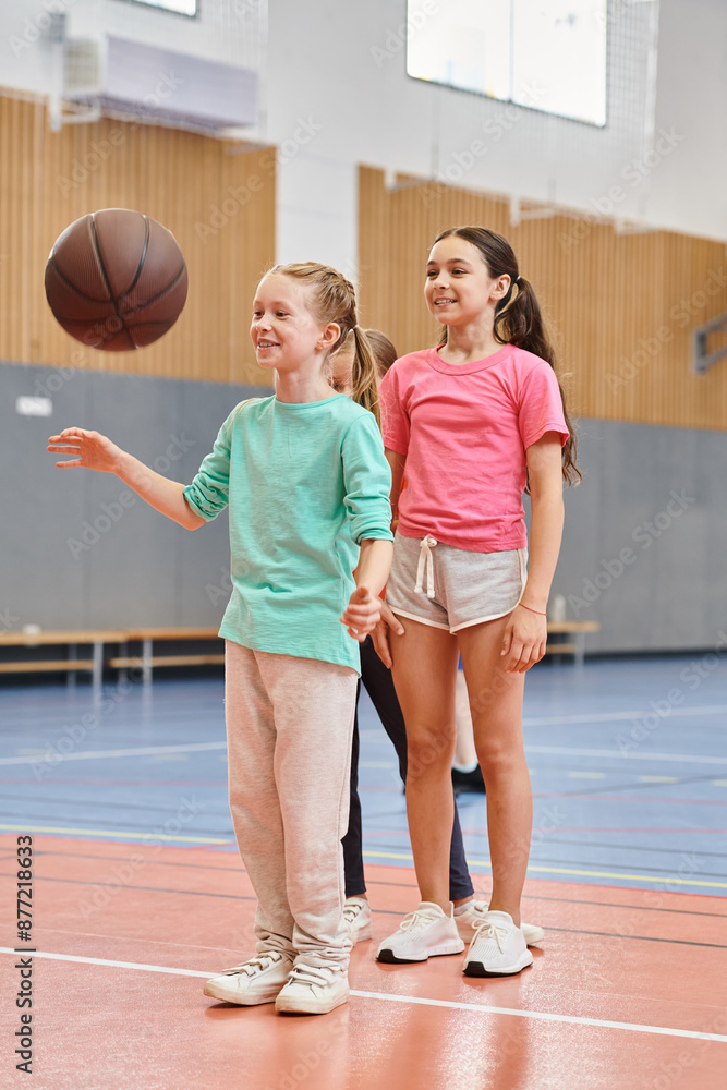Naklejka premium girls stand confidently atop a basketball court, listening attentively to their male teachers instructions.