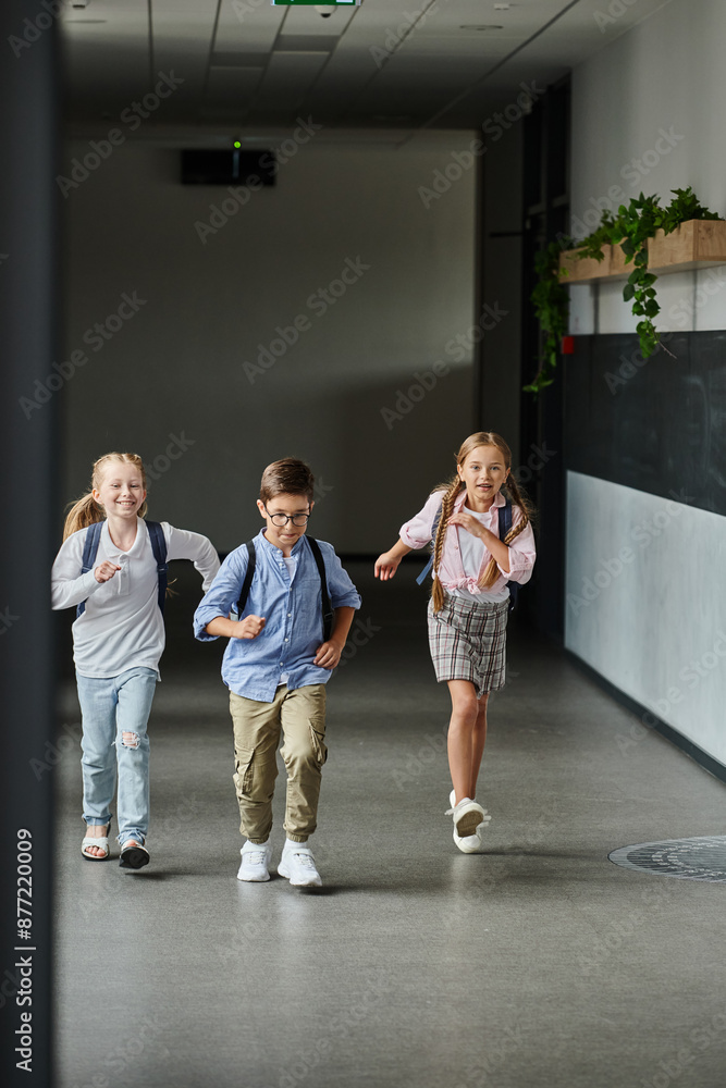 Fototapeta premium A group of young children laughing and running through a hallway, filled with excitement and energy.