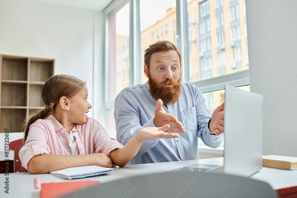 A man, acting as a teacher, attentively guides a young girl while they sit together at a desk in a bright, lively classroom setting. A man, acting as a teacher, attentively guides a young girl while they sit together at a desk in a bright, lively classroom setting.