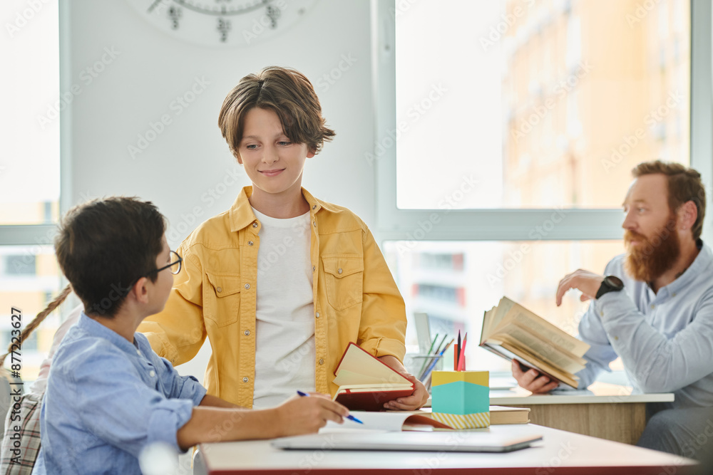 A group of individuals, including a man teacher, are engrossed in studying books together at a brightly lit classroom table. A group of individuals, including a man teacher, are engrossed in studying books together at a brightly lit classroom table.