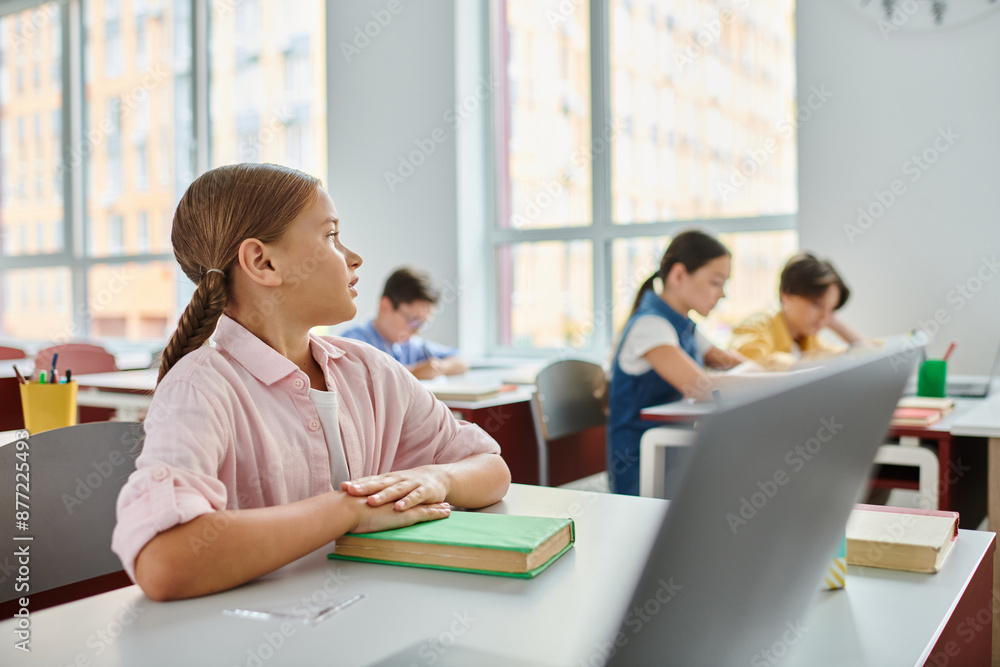 A girl immersed in her work, sits at a desk with a laptop open in front of her, focused and engaged in the digital world. A girl immersed in her work, sits at a desk with a laptop open in front of her, focused and engaged in the digital world.