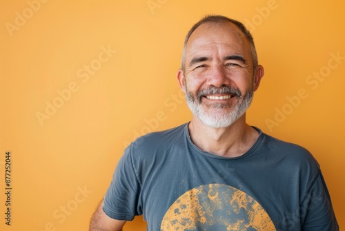 Portrait of a happy man in his 40s sporting a vintage band t-shirt over solid color backdrop