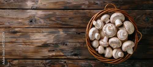 Freshly cut white mushrooms ideal for various dishes are displayed on a wooden background in a brown basket Top view with copy space image available