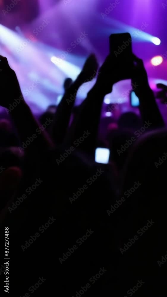 A person holding a smartphone, capturing the energy of a live concert A person holding a smartphone, capturing the energy of a live concert