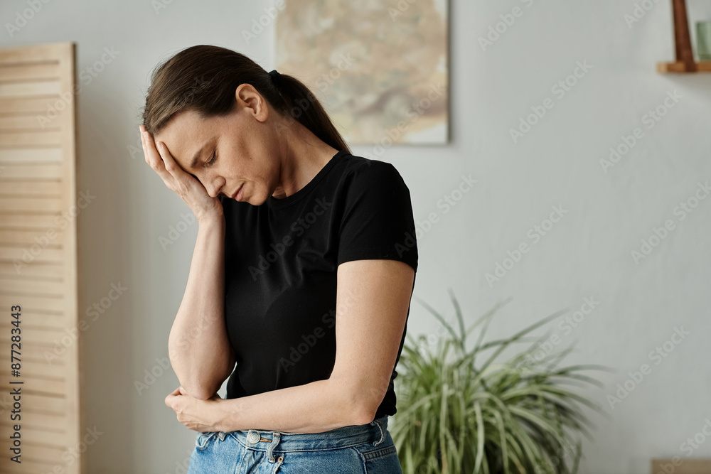 Middle aged woman in distress holds head while standing in living room. Middle aged woman in distress holds head while standing in living room.