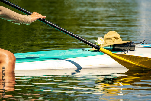 Photography Summer time vibe: a water lily, sunhat, and water bottle, sit on a standup paddl