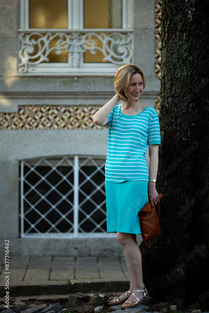 A woman stands on the street next to a typical Portuguese house. A woman stands on the street next to a typical Portuguese house.
