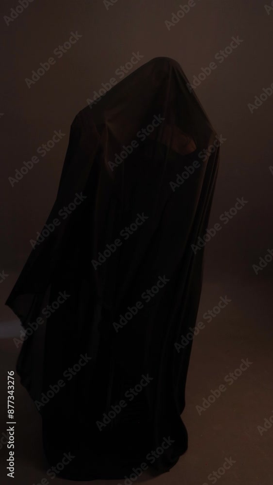 a mystical priestess under a black veil, a woman in black on a dark background, the wind sways the fabric on her face a mystical priestess under a black veil, a woman in black on a dark background, the wind sways the fabric on her face