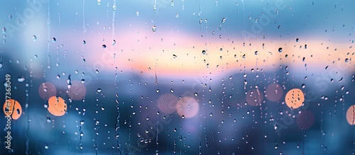 Close up image of raindrops on a window during a summer storm creating a moody vibe ideal for Instagram with a blurred background showing the sky Focus on the wet glass with tiny droplets featuring c photo