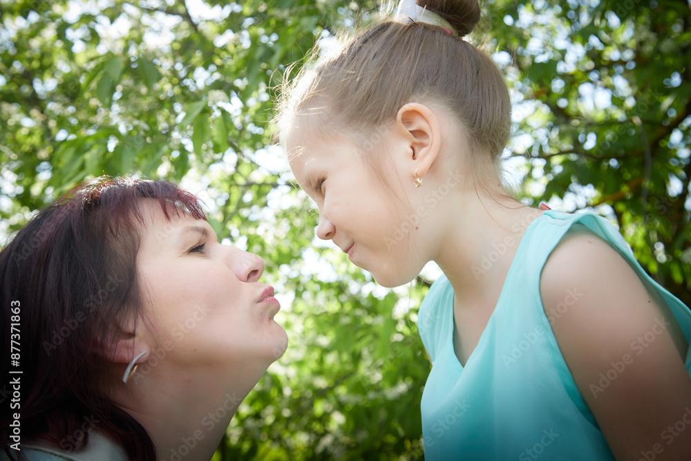 Happy mother and daughter enjoying rest, playing and fun on nature on a green lawn and with a blooming apple tree in the background. Woman and girl resting outdoors in summer and spring day Happy mother and daughter enjoying rest, playing and fun on nature on a green lawn and with a blooming apple tree in the background. Woman and girl resting outdoors in summer and spring day