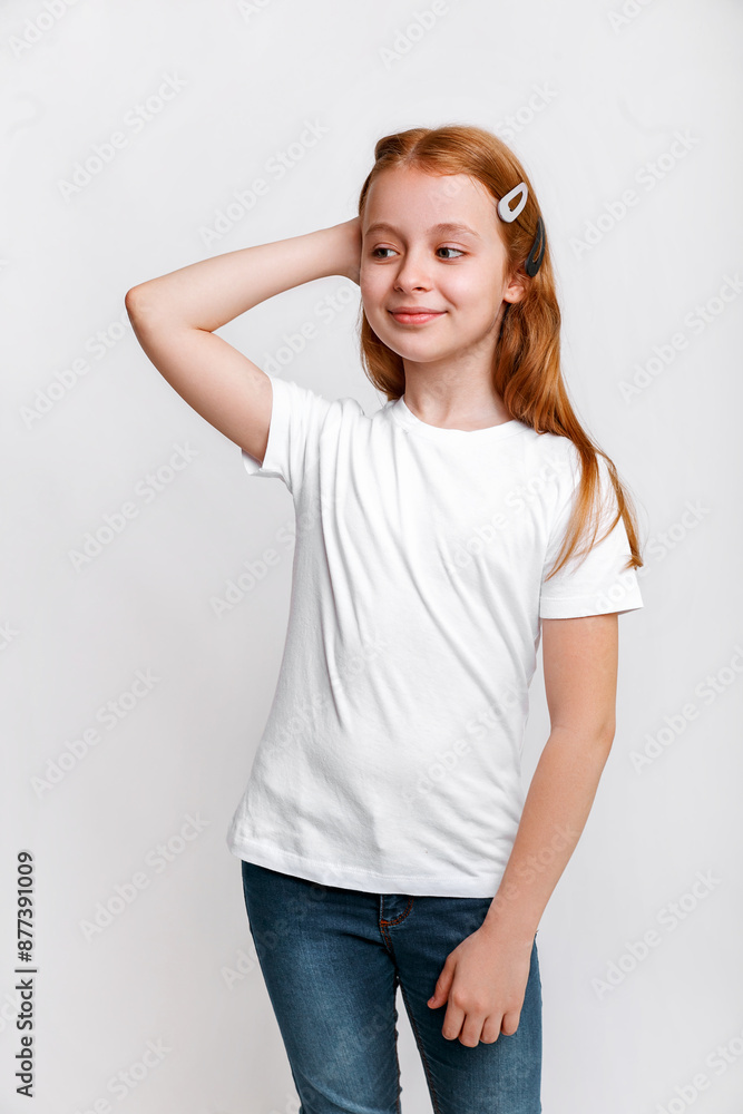 Redhead little girl model posing and smiling in white t-shirt on white studio background. Fashion kid Redhead little girl model posing and smiling in white t-shirt on white studio background. Fashion kid