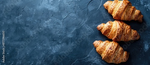 Panel kuchenny z motywem Three croissants artfully arranged on a dark blue slate background with meal captured in a top down perspective for a striking copy space image
