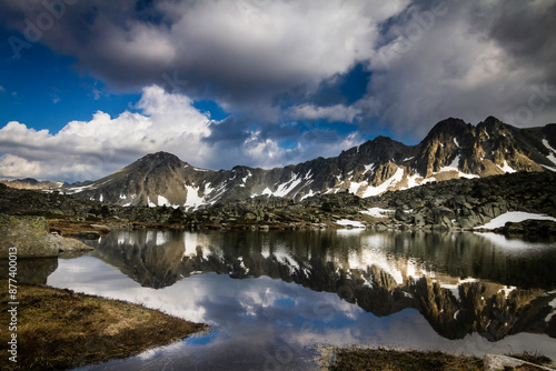 Lac de montagne dans les Pyrénées Andorranes avec encore des névés sur les sommets 