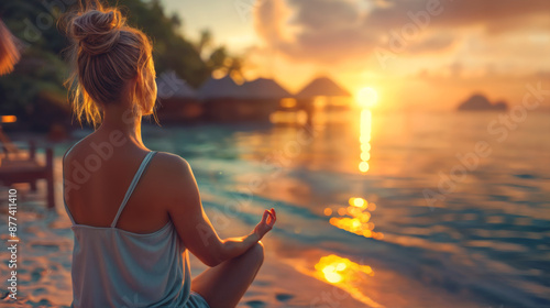 Fototapeta Naklejka Na Ścianę i Meble -  Young woman practicing yoga by the sea during sunset in the summertime