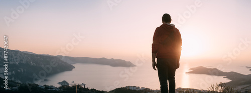 Photography A Caucasian guy stands high on a cliff above a small town and looks at the sun s