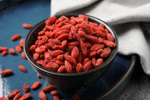 Dried goji berries in bowl on table, closeup photo