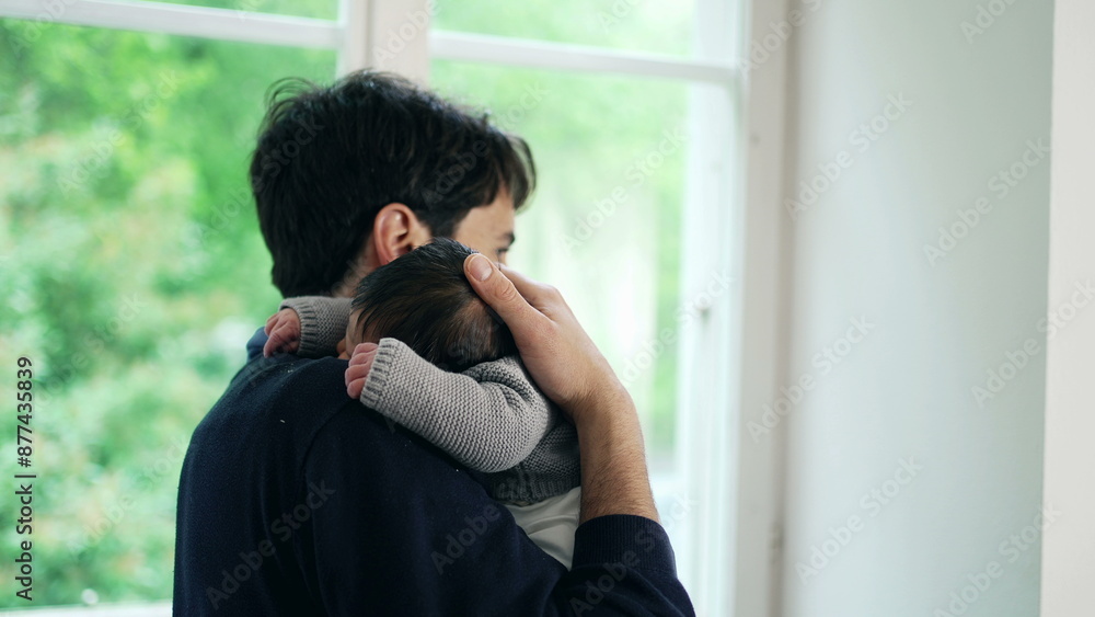 Father cradling newborn baby in arms, looking out window, tender moment, daytime, family love, natural light, indoor scene, parent-child bond, serene and peaceful, young fatherhood Father cradling newborn baby in arms, looking out window, tender moment, daytime, family love, natural light, indoor scene, parent-child bond, serene and peaceful, young fatherhood