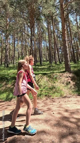 Woman and girl hikers walking on a trail in a forest, in the Canencia mountain, the Guadarrama National Park, in Madrid, Spain. Vertical shot
