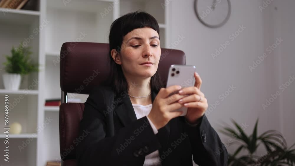 Positive young caucasian woman relaxing at work typing browsing products in internet online store reading news or social media profile on smartphone while take a break at office workplace indoors Positive young caucasian woman relaxing at work typing browsing products in internet online store reading news or social media profile on smartphone while take a break at office workplace indoors