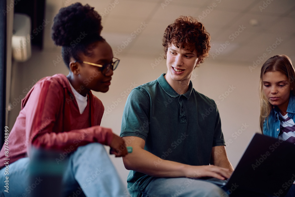 Obraz premium Young students cooperating while using laptop and learning in classroom.