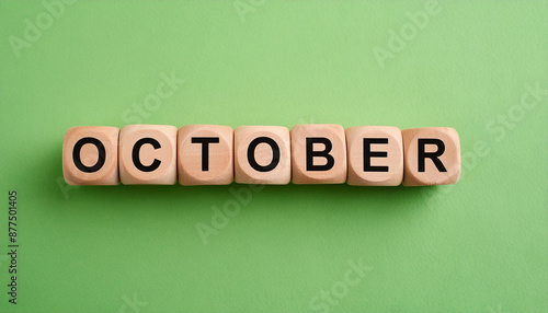 Wooden cubes with text OCTOBER on green backdrop. Autumn season. Month of year. Close-up. Flat lay