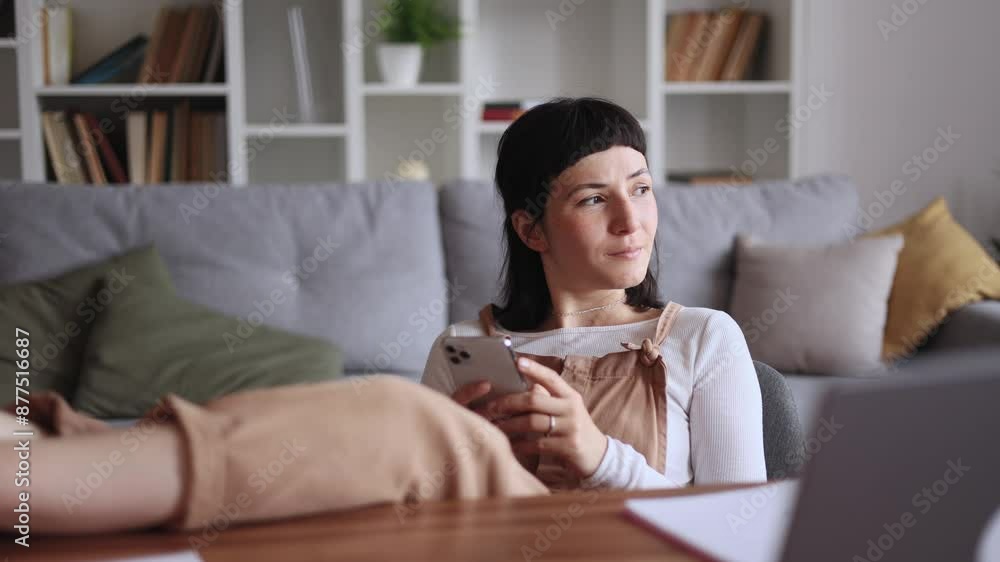 Positive young caucasian woman student or freelancer relaxing at home typing browsing products in internet online store reading news or social media profile on smartphone while take a break indoors Positive young caucasian woman student or freelancer relaxing at home typing browsing products in internet online store reading news or social media profile on smartphone while take a break indoors