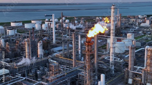Aerial view of a chemical plant at sunset. Drone shot. Curling fire and cumin smoke filling the sky. Smoking chimneys from the factory. Chimneys of an oil refinery at sunrise pollute the environment