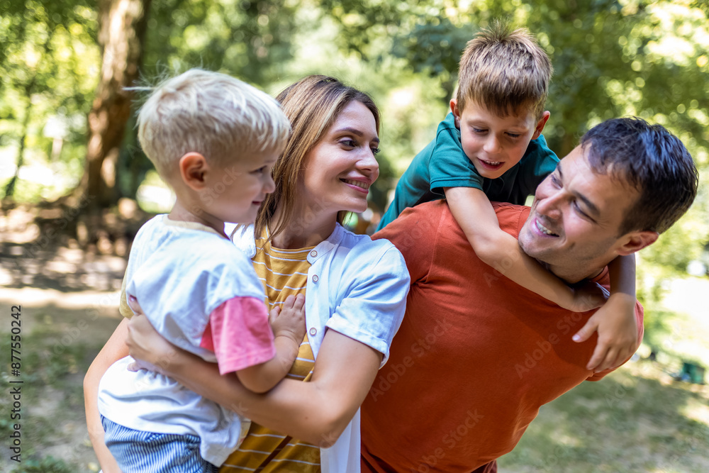 Family of four bonding in the park. Mother and father hugging with their sons. Family of four bonding in the park. Mother and father hugging with their sons.