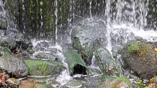 video with small waterfall and stones in moss. falling water slow motion