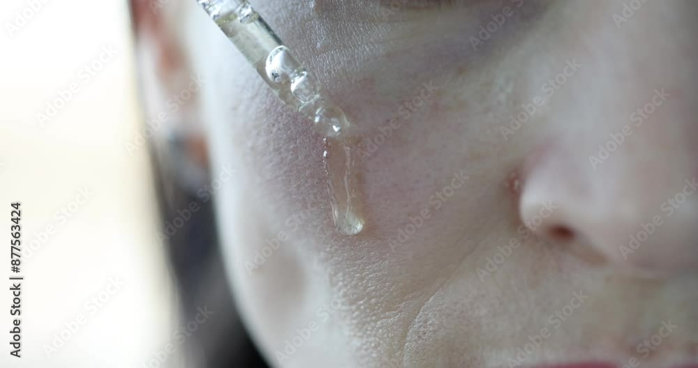 Woman dripping clear oil on face. Facial skin care concept Woman dripping clear oil on face. Facial skin care concept