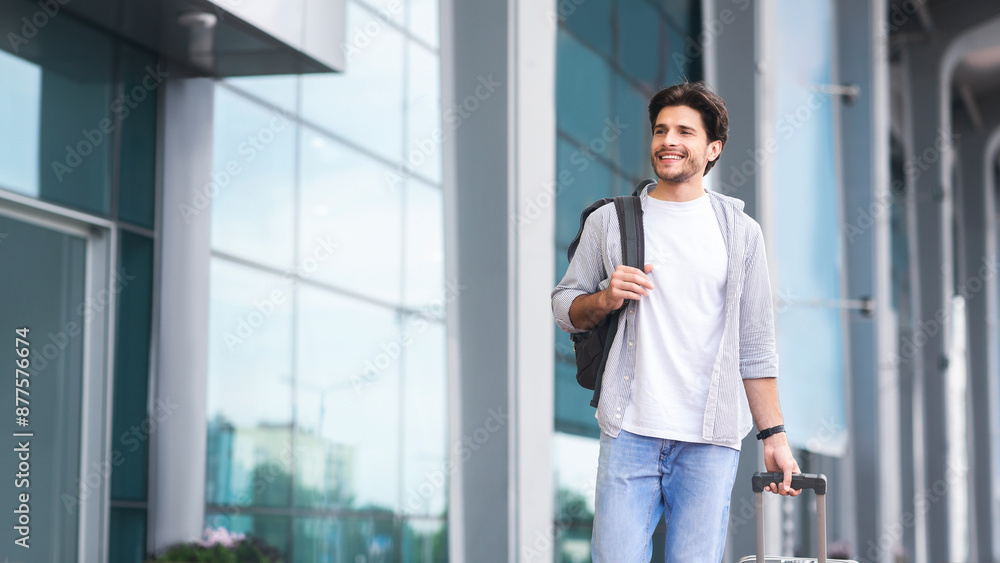 Young man arriving to airport at new destination, standing outside of terminal, ready to explore the city, free space Young man arriving to airport at new destination, standing outside of terminal, ready to explore the city, free space