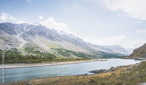 Blue mirror water of Panj river between Afghanistan and Tajikistan, river flows in a valley among rocky mountains in the Pamirs, panoramic landscape for background photo