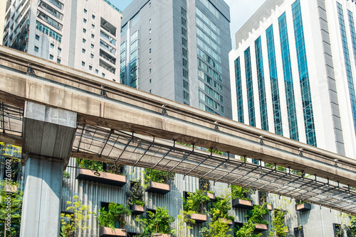 Photography Modern skyscrapers and metro bridge with green plants on urban building facade in Kuala Lumpur city, Malaysia