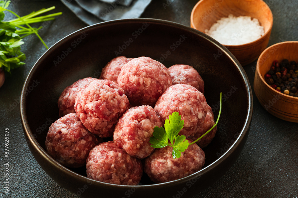 Raw ground beef meatballs in black bowl Raw ground beef meatballs in black bowl