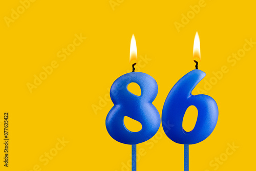 Blue birthday candle on yellow background - Number 86