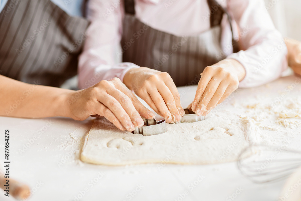 Cropped of a pair of hands using cookie cutters to cut out shapes from dough. The dough is covered in a thin layer of flour, and the cookie cutters are leaving small, perfect circles in the dough Cropped of a pair of hands using cookie cutters to cut out shapes from dough. The dough is covered in a thin layer of flour, and the cookie cutters are leaving small, perfect circles in the dough